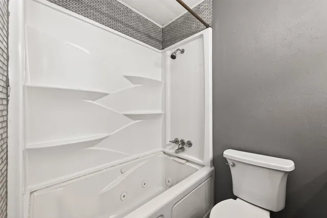 a white toilet sitting next to a bathroom sink and tub