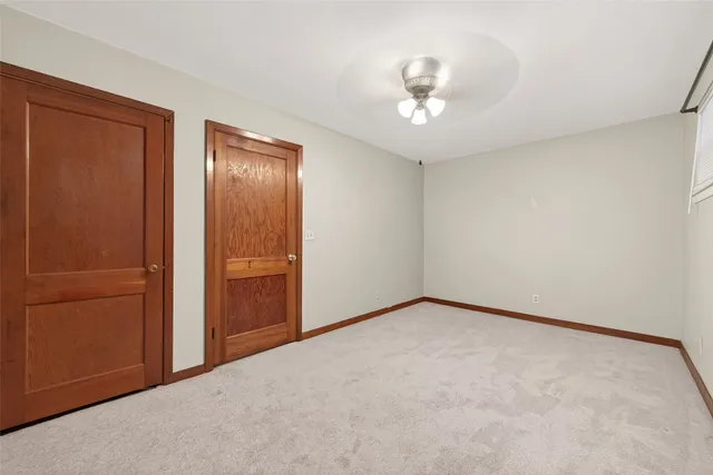 an empty room with a chandelier fan and closet area