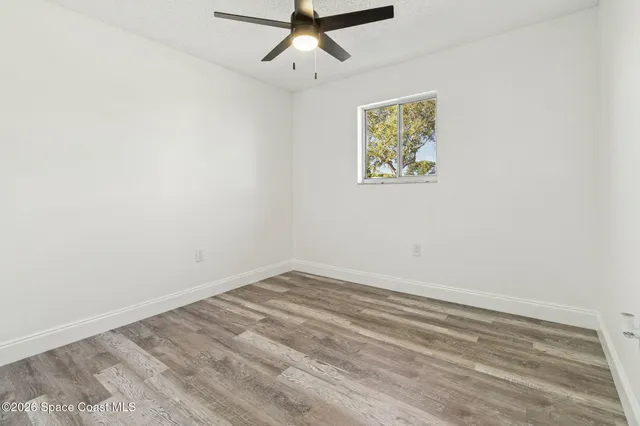 an empty room with a window and a ceiling fan