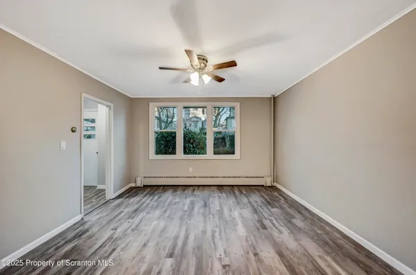 a view of empty room with wooden floor and fan