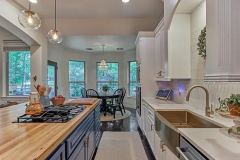 a kitchen with a stove a sink a kitchen island with a dining table and chairs