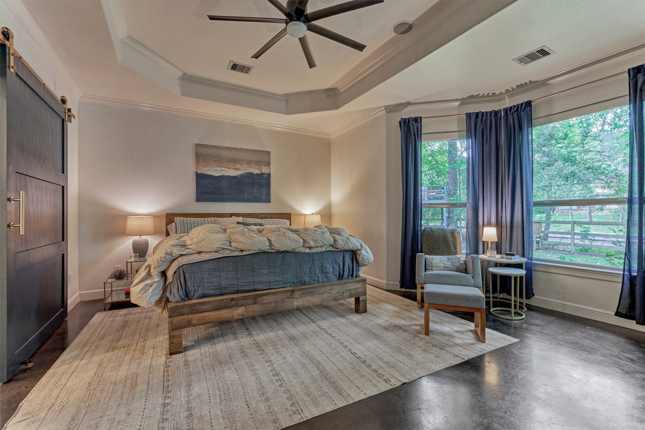 16727 Boothill Road Stagecoach, TX 77355 - Photo 20 of 44 The primary bedroom boasts a trayed ceiling and barn door leading to the luxe bathroom.