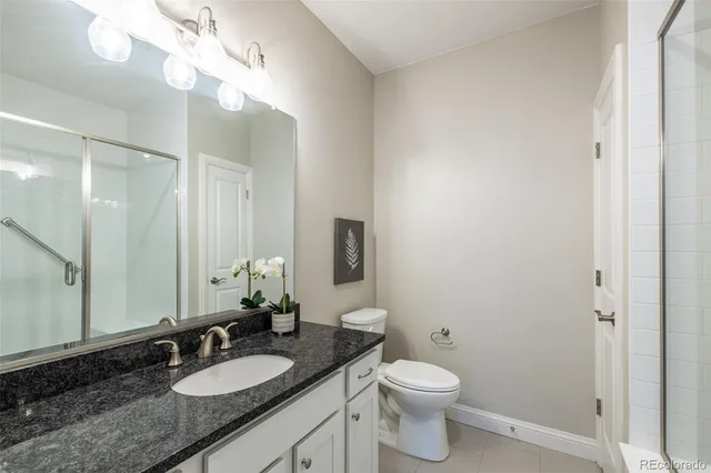 a bathroom with a granite countertop toilet sink and mirror