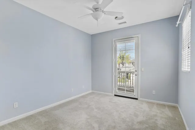 an empty room with windows and ceiling fan