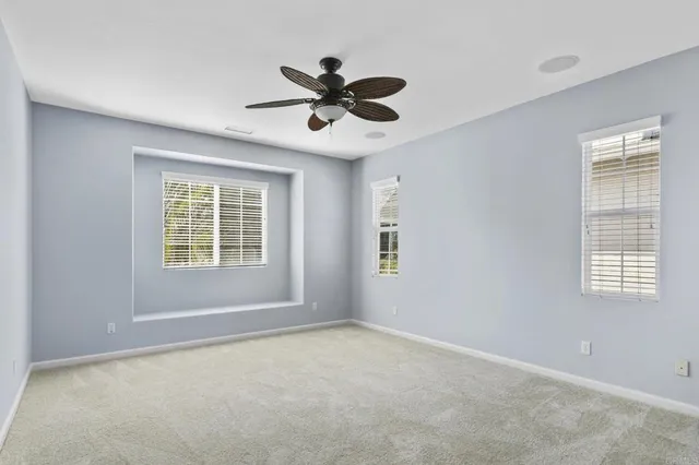 a view of an empty room with a window and a ceiling fan