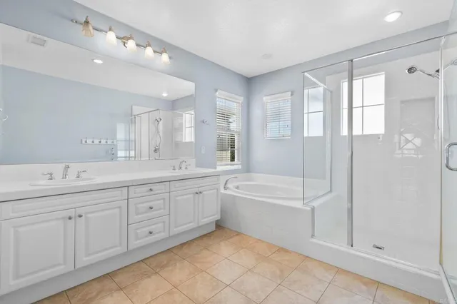 a spacious bathroom with a double vanity sink a mirror and a bathtub