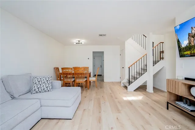 a living room with furniture and a dining table with wooden floor