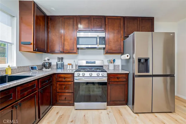 a kitchen with granite countertop a refrigerator stove top oven and sink