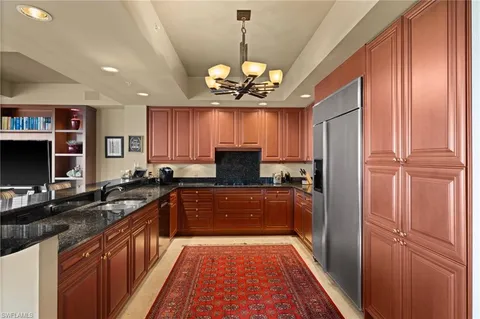 a kitchen with stainless steel appliances granite countertop a refrigerator a sink dishwasher a stove and a dining table