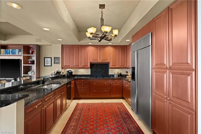 a kitchen with stainless steel appliances granite countertop a refrigerator a sink dishwasher a stove and a dining table