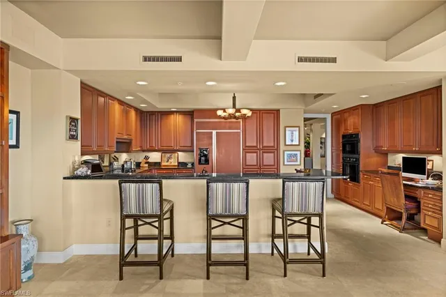 a kitchen with stainless steel appliances kitchen island granite countertop a table chairs sink and cabinets