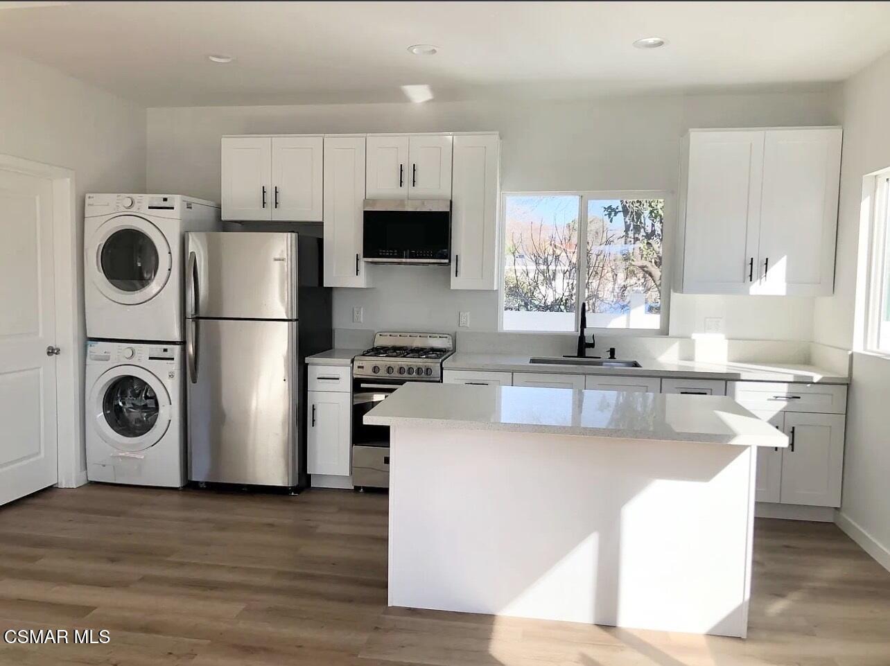 14083 La Rue Street San Fernando, CA 91340 - Photo 3 of 5 a kitchen with stainless steel appliances granite countertop a refrigerator a stove top oven a sink and dishwasher with wooden floor