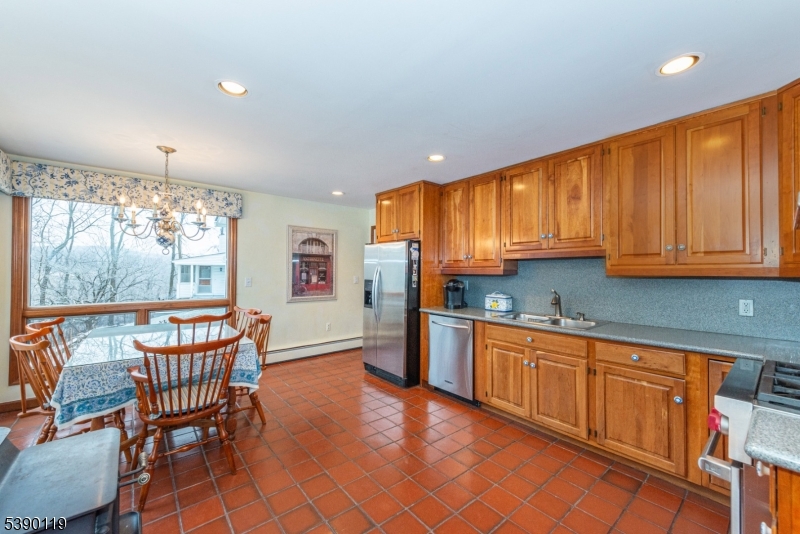 107 Clove Road, Unit 3 Wantage, NJ 07461 - Photo 14 of 45 a kitchen with stainless steel appliances granite countertop a refrigerator a stove top oven and a dining table with wooden cabinet