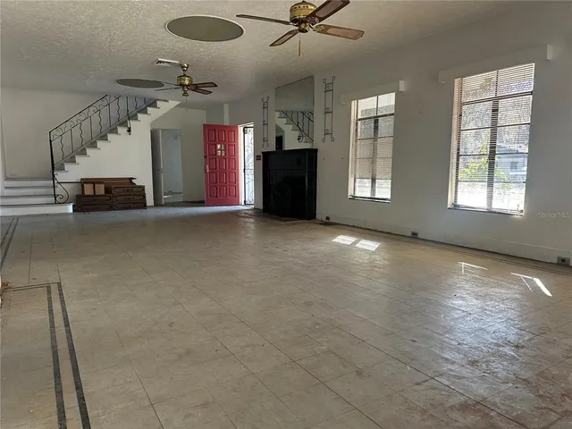 an empty room with ceiling fan and windows