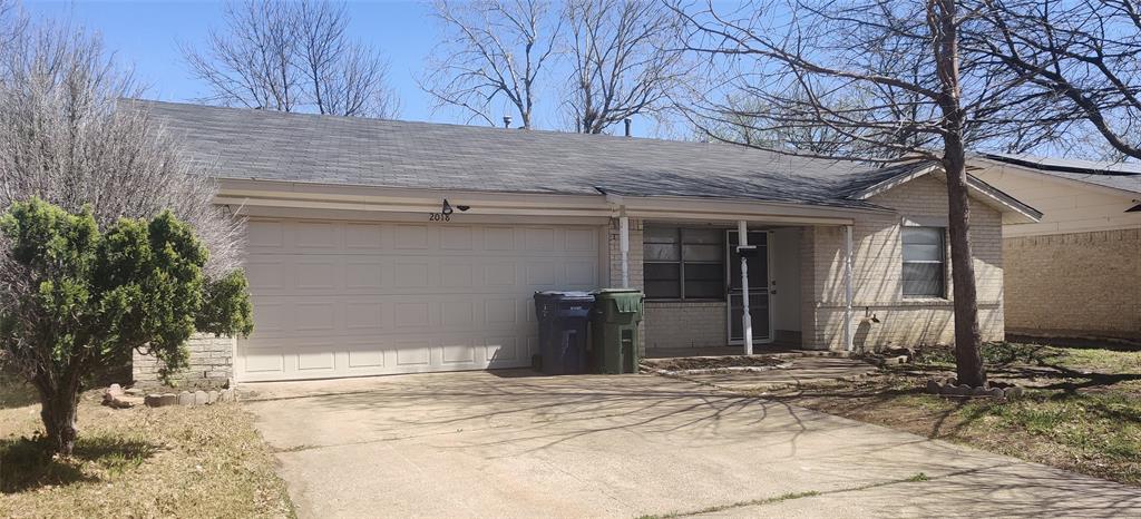 View of front of property with concrete driveway, a garage, brick siding, and roof with shingles