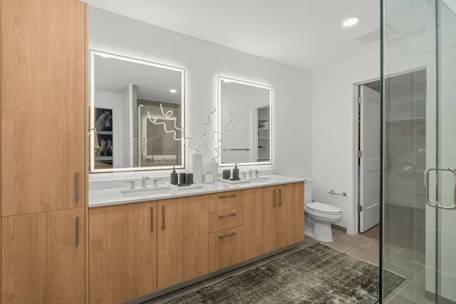a bathroom with a double vanity sink toilet and shower