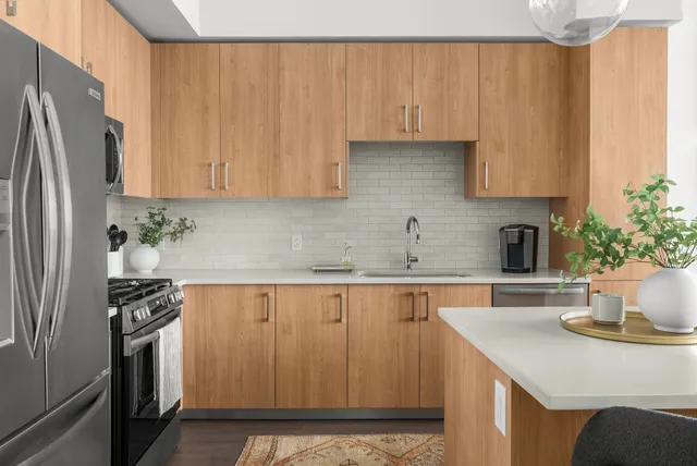 a kitchen with stainless steel appliances a refrigerator a sink a stove and white cabinets