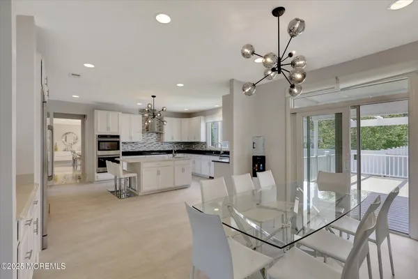 a open kitchen with stainless steel appliances granite countertop a stove a sink a refrigerator and white cabinets with wooden floor