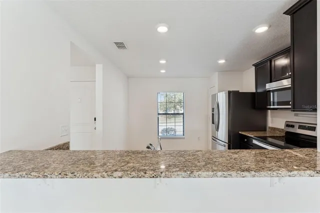 a kitchen with stainless steel appliances granite countertop a refrigerator sink and stove