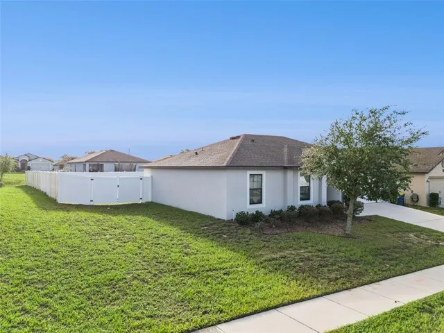 a view of a house with a yard and a large tree