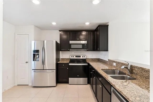 a kitchen with stainless steel appliances granite countertop a sink a stove a refrigerator a washer and dryer