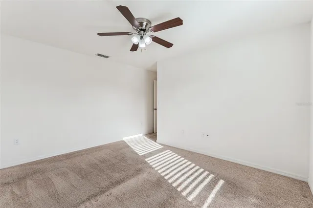 an empty room with a ceiling fan and wooden floor