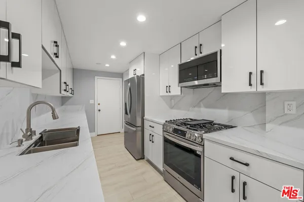 a kitchen with stainless steel appliances granite countertop a stove a sink and a microwave