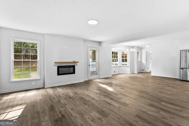 a view of an empty room with a window and wooden floor