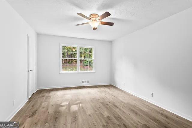 an empty room with wooden floor and windows