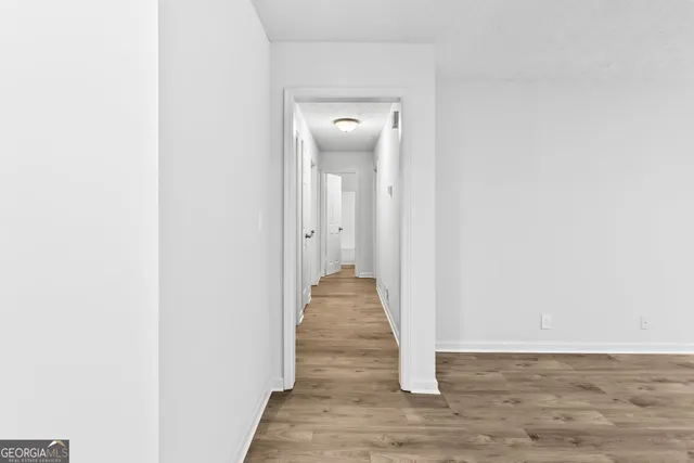 a view of a hallway with wooden floor and closet
