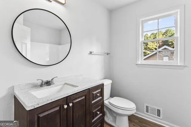a bathroom with a granite countertop toilet a sink and a mirror
