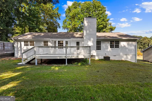 a view of a house with a wooden deck and a yard