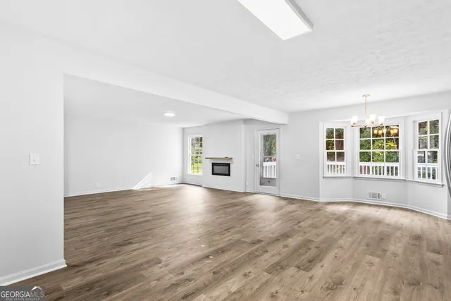a view of empty room with wooden floor and windows