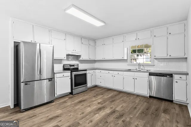 a kitchen with granite countertop white cabinets and stainless steel appliances