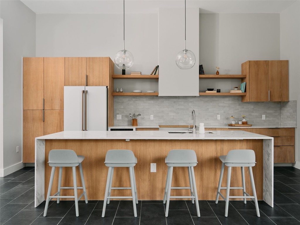 412 Kemp Street Austin, TX 78741 - Photo 13 of 37 Kitchen with light stone countertops, modern cabinets, a kitchen breakfast bar, high end fridge, and dark tile patterned flooring