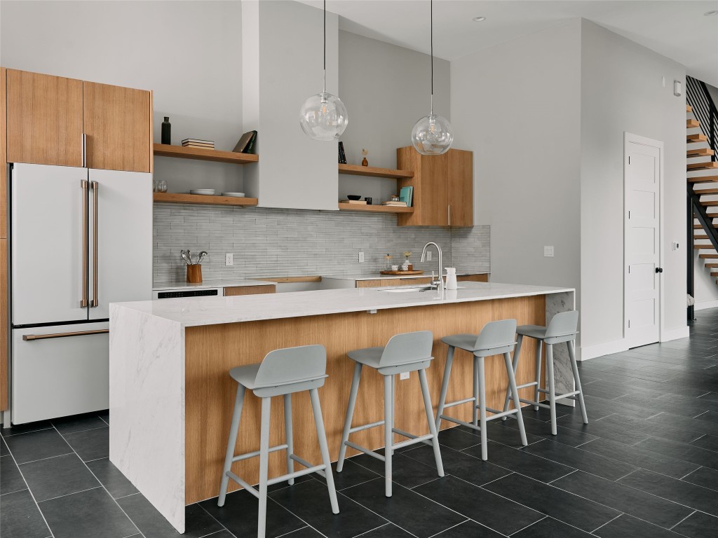 412 Kemp Street Austin, TX 78741 - Photo 14 of 37 Kitchen featuring high end white refrigerator, a kitchen bar, tasteful backsplash, hanging light fixtures, and a high ceiling