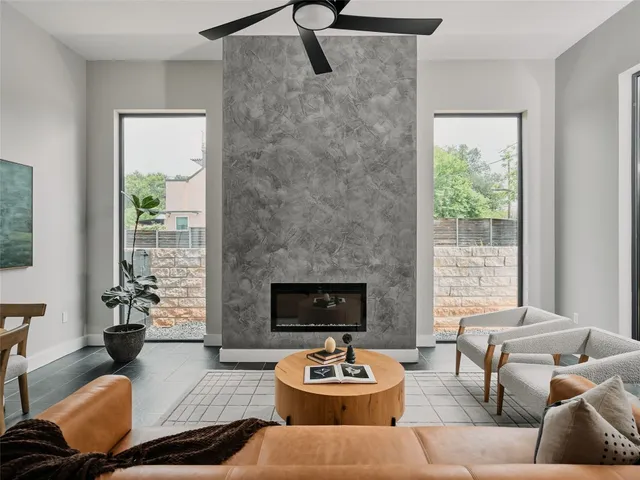 a living room with furniture a fireplace and a floor to ceiling window