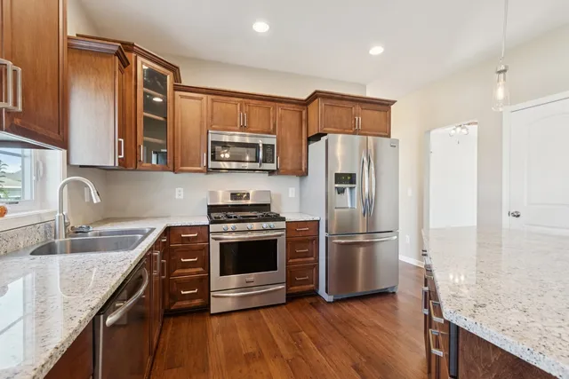 a kitchen with stainless steel appliances granite countertop a refrigerator sink and stove
