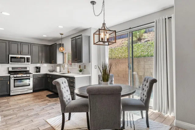 a kitchen with granite countertop wooden floor dining table and stainless steel appliances
