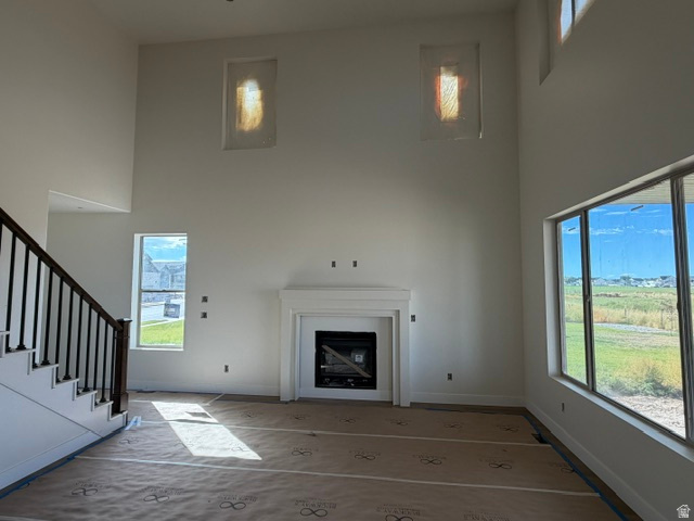 1931 South Fitzroy Road Ogden, UT 84401 - Photo 4 of 12 Two-story living area with a fireplace, large windows, and a staircase featuring a dark wood handrail and black balusters
