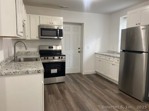 a kitchen with granite countertop a refrigerator stove and microwave