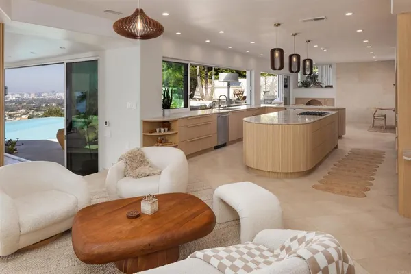 a living room with furniture kitchen view and a chandelier