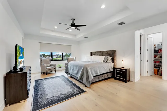 a spacious bedroom with a bed a dresser and a chandelier