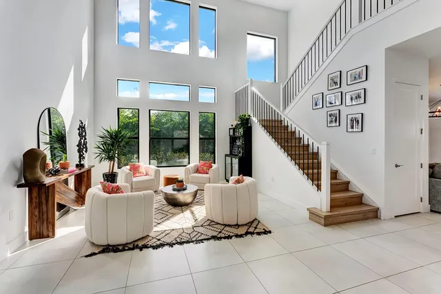 a room with lots of white furniture and a floor to ceiling window
