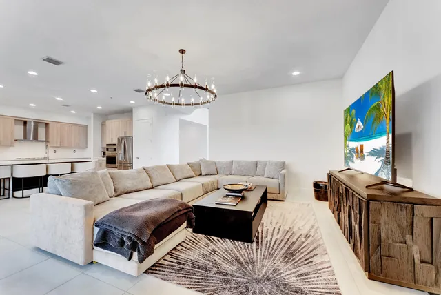 a living room with furniture a chandelier and a flat screen tv
