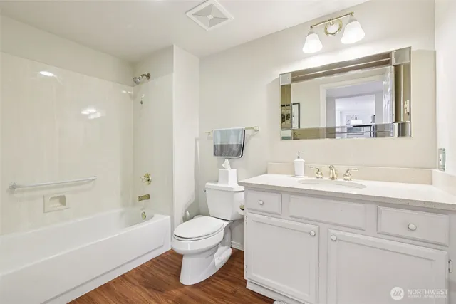 a bathroom with a toilet a sink a mirror a bathtub and vanity