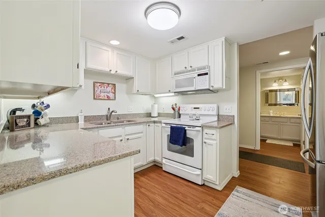 a kitchen with granite countertop a sink cabinets and wooden floor