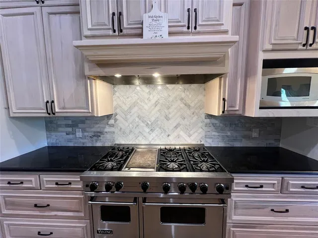 a kitchen with granite countertop white cabinets and black appliances