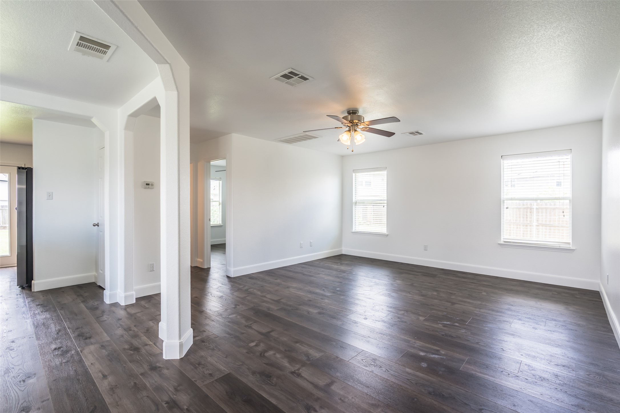 1013 Ranchero Road Leander, TX 78641 - Photo 8 of 30 Rich dark wood floors ground an airy, open-concept living space with clean white walls.