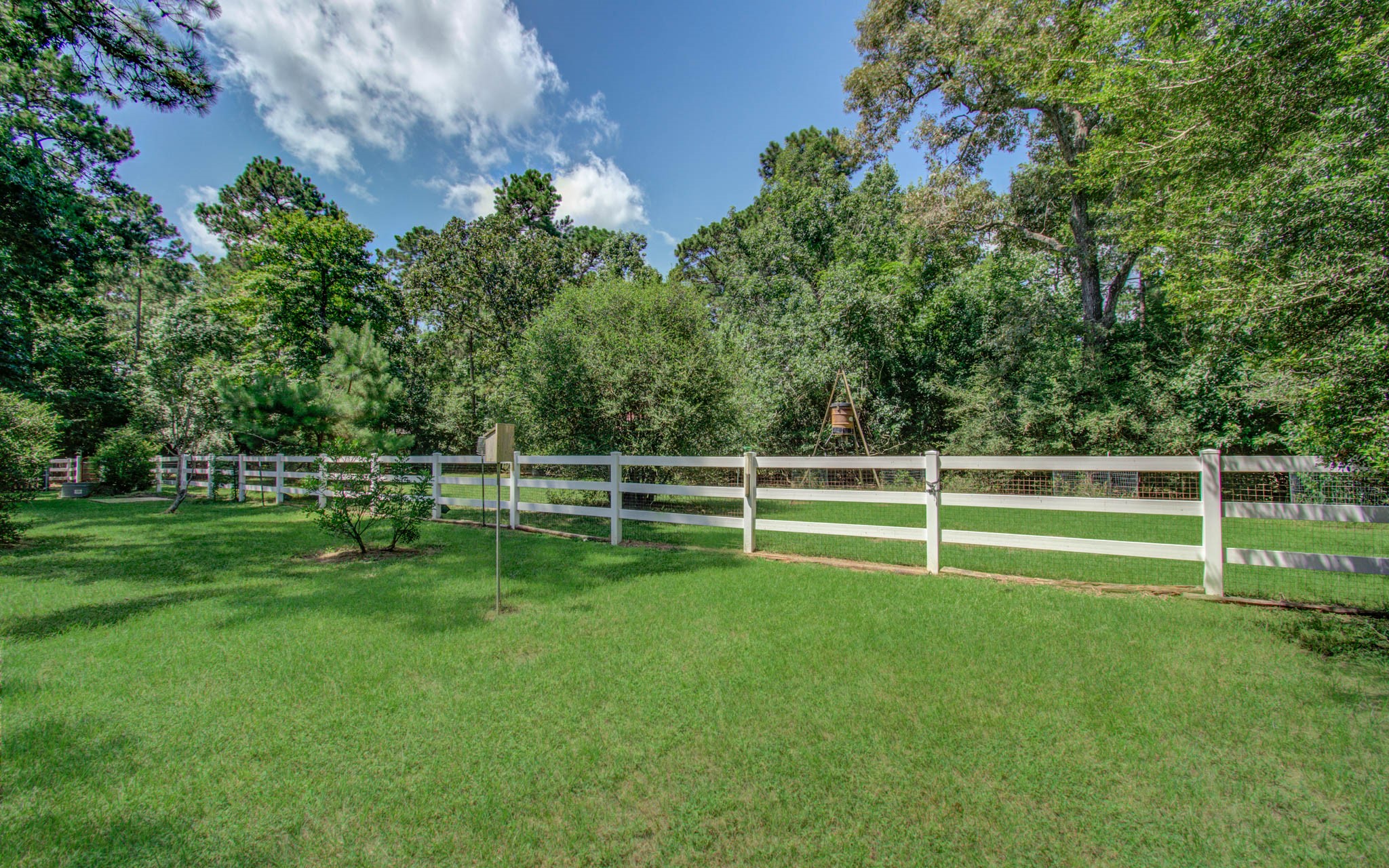 20203 Timber Ridge Drive Magnolia, TX 77355 - Photo 32 of 49 Spacious, fully fenced backyard with lush green lawn, mature trees, and peaceful wooded privacy. Classic white fencing creates a charming setting with plenty of room for entertaining, gardening, pets, or future outdoor enhancements.